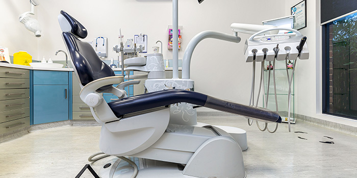 A dental chair in a dental office with dental equipment around the chair